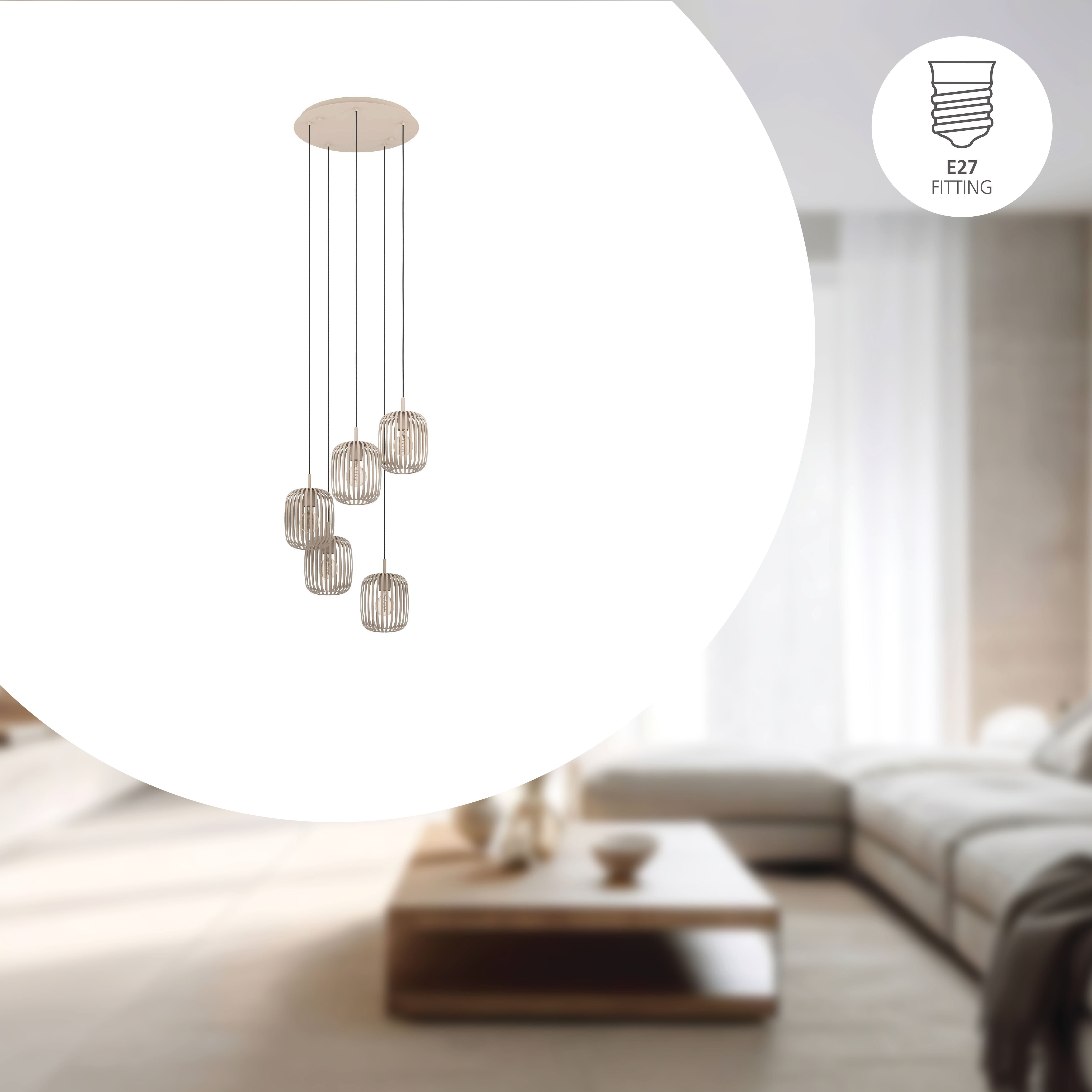 Een moderne kroonluchter met vijf lampen hangt boven een woonkamer. De lichten zijn cilindrisch, in een kooi. De achtergrond is wazig.