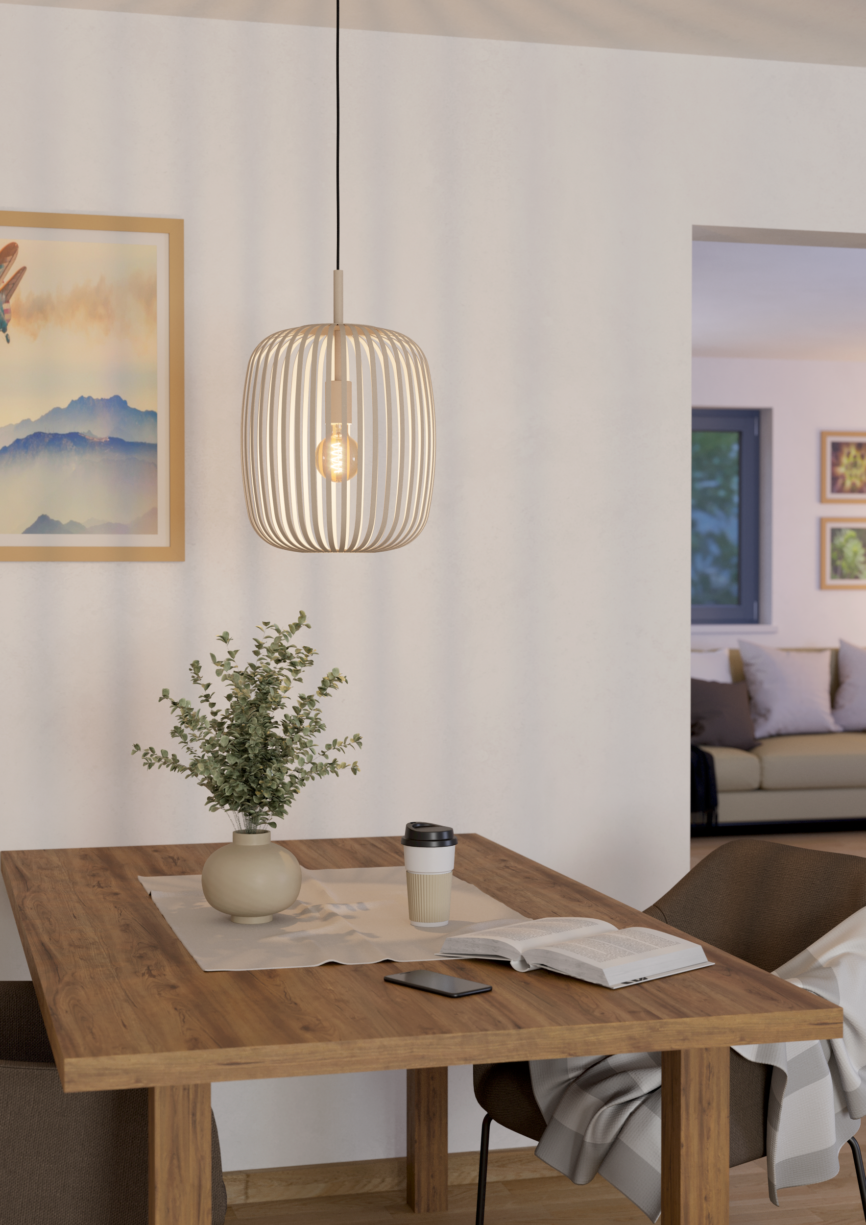 Een eettafel met een vaas met planten, een beker, een boek en een mobiele telefoon. Een lamp hangt erboven.