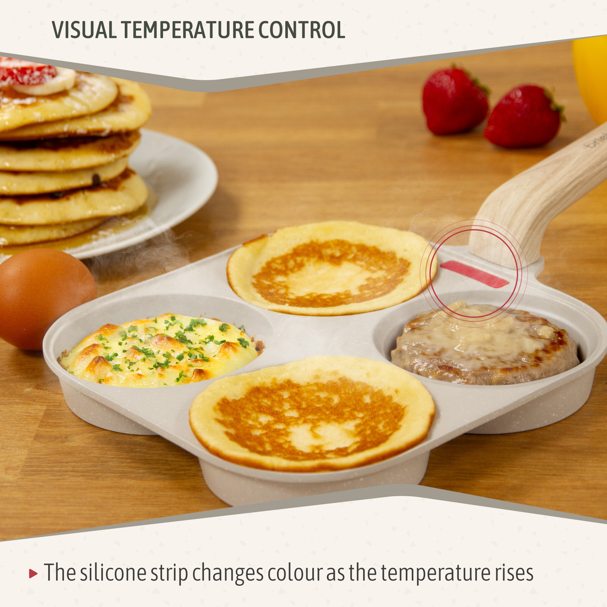 Panqueques, huevo, fresas y comida en una sartén. La sartén tiene un mango y una tira de silicona que cambia de color con la temperatura.
