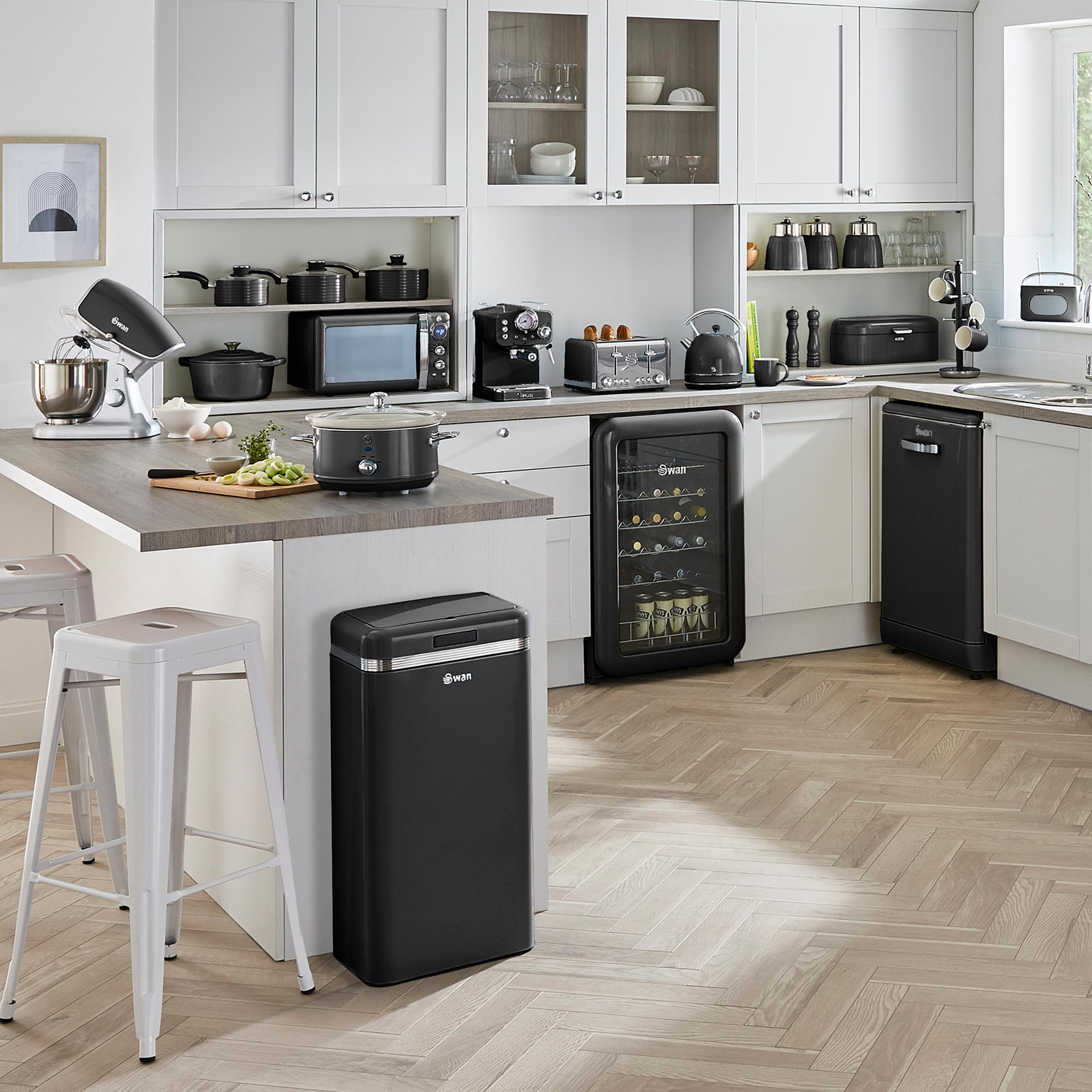 Moderne Küche mit weißen Schränken, schwarzen Geräten und Holzboden. Enthält Mixer, Mikrowelle und Kühlschrank.