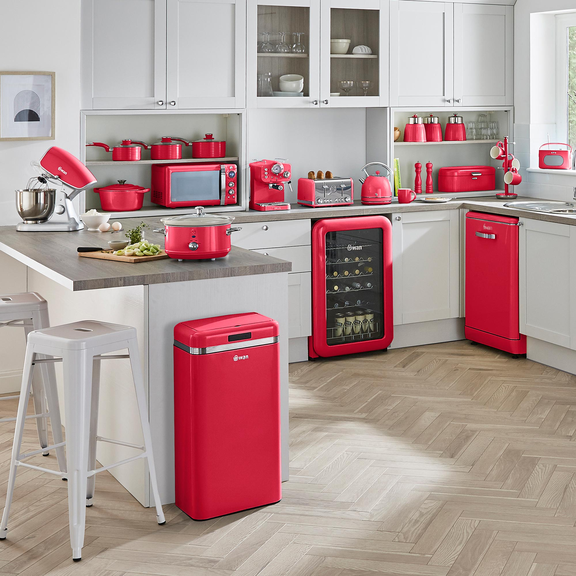 Eine Küche mit weißen Schränken und roten Geräten. Enthält eine Mikrowelle, einen Toaster, einen Mixer und einen Kühlschrank.