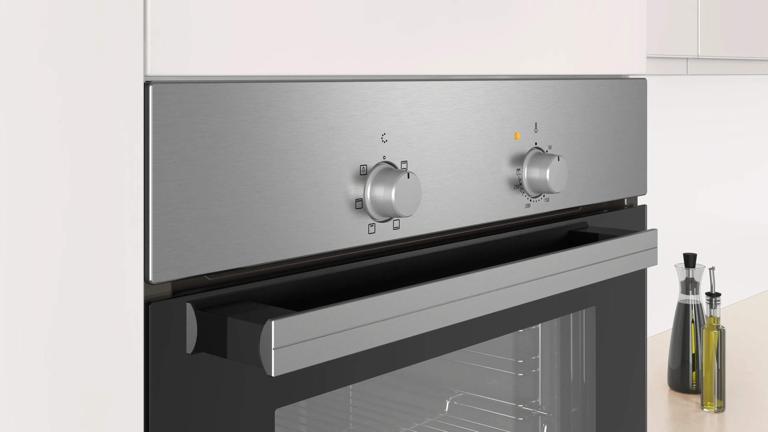 Piekarnik ze stali nierdzewnej z pokrętłami i otwartymi drzwiami. Dwie butelki oleju na blacie.