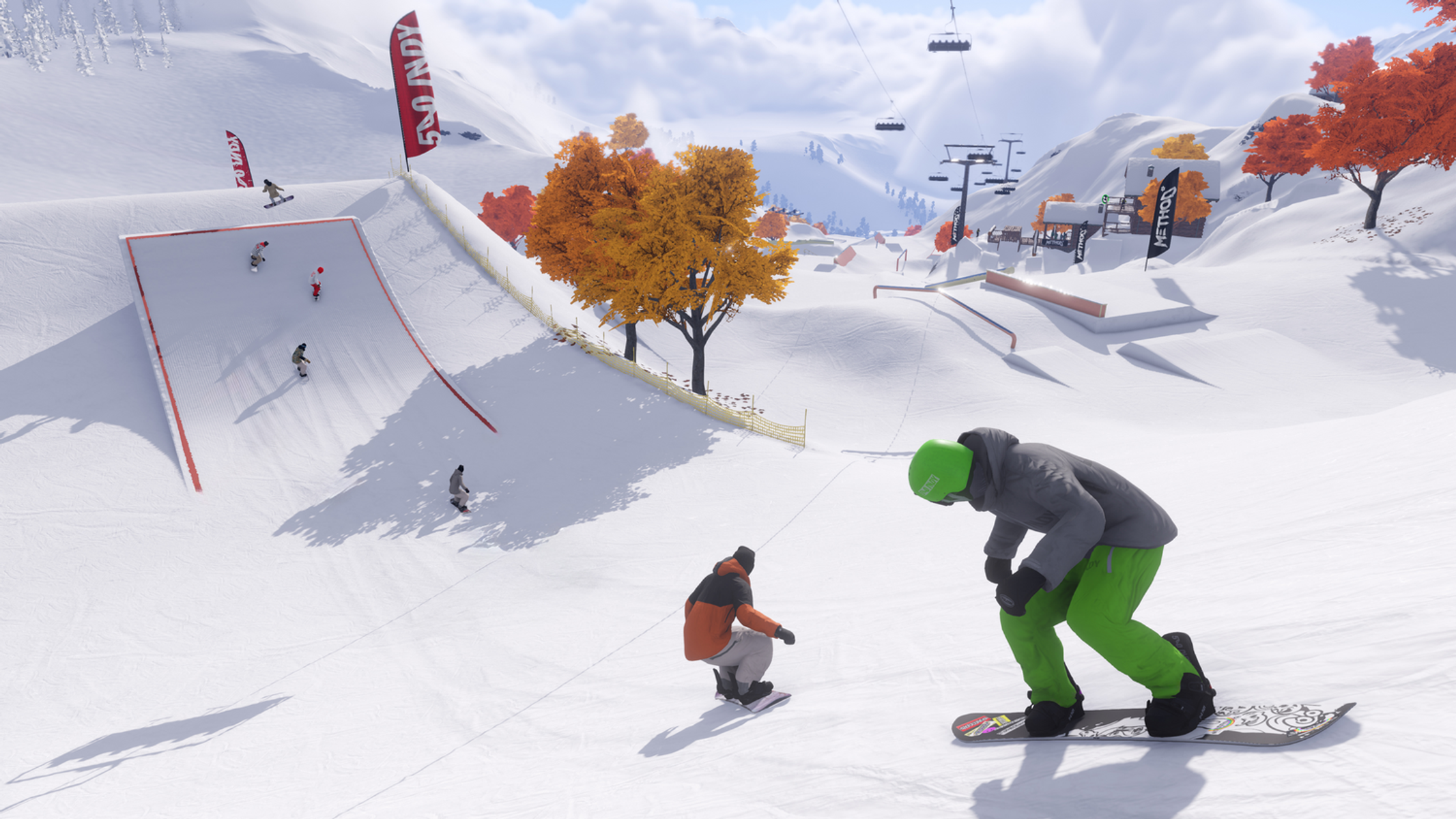 Snowboardziści na zaśnieżonym stoku. Osoba w zielonym stroju przygotowuje się do jazdy. Inni zjeżdżają z ramp z flagami i drzewami w tle.