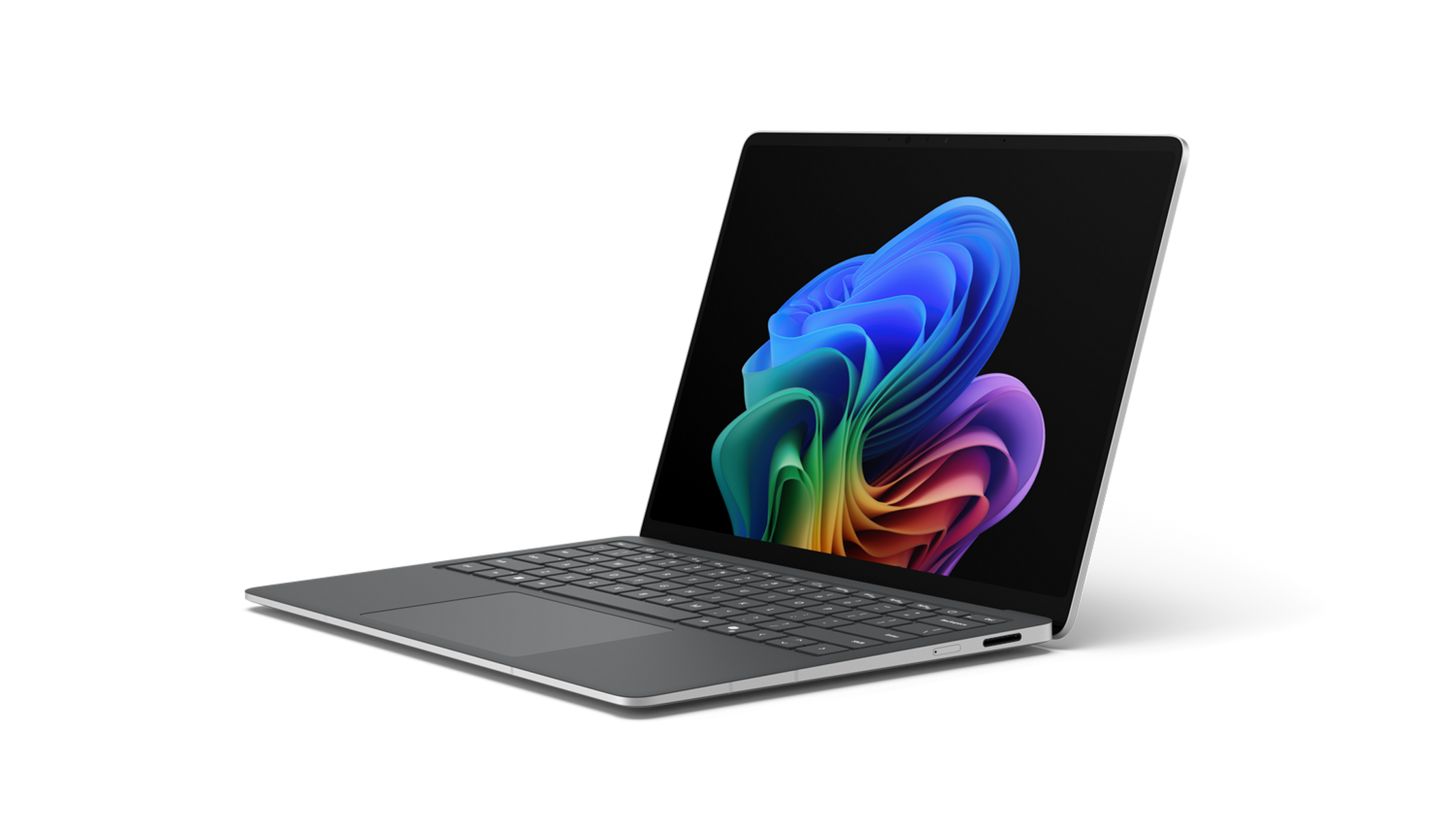 Portátil sobre fondo negro. La pantalla muestra un diseño abstracto colorido. El teclado es visible. Marco plateado alrededor de la pantalla.