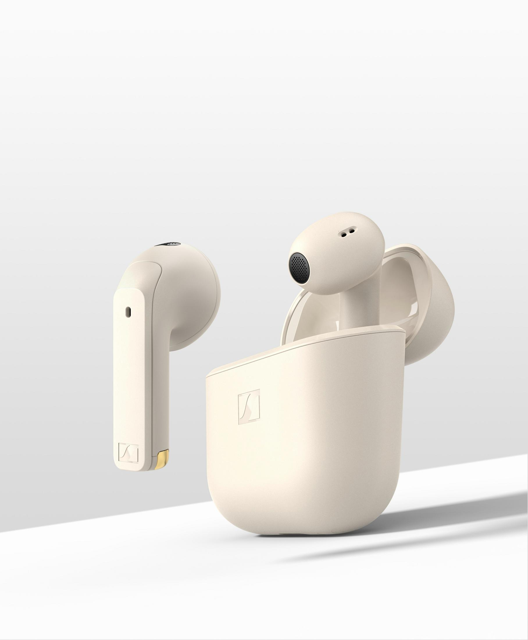 Auriculares inalámbricos beige y estuche de carga sobre fondo blanco. Un auricular está separado. Estuche abierto.