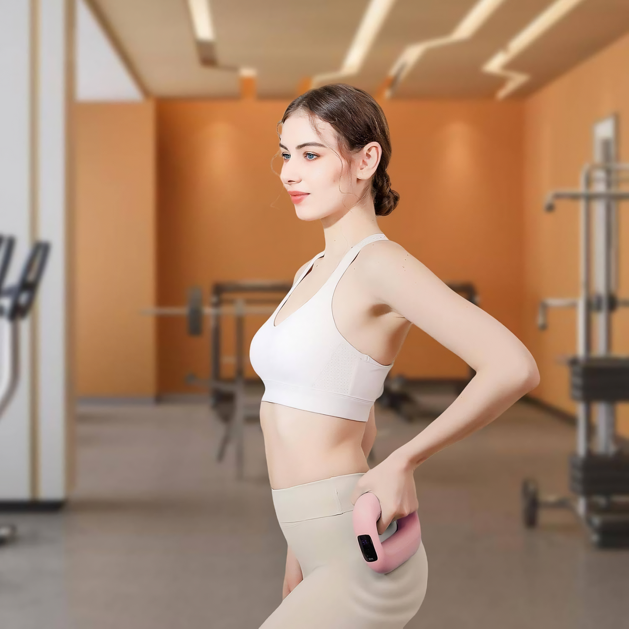 Eine Frau in Sportkleidung hält ein rosa Trainingsgerät. Im verschwommenen Hintergrund sind Fitnessgeräte zu sehen.