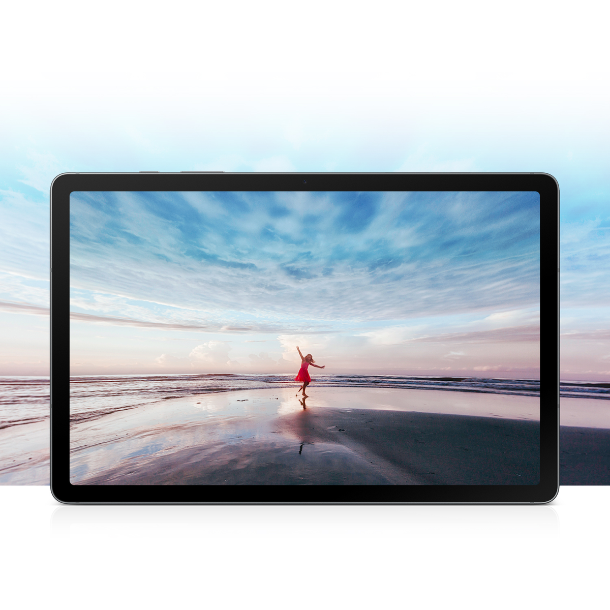 Tablet wyświetla scenę z plaży. Osoba w czerwonej sukience tańczy na brzegu pod zachmurzonym niebem, blisko wody.