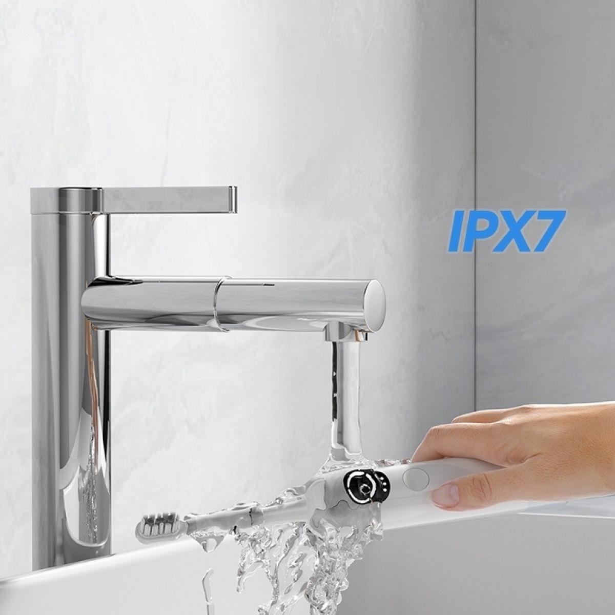 Eine Hand hält eine weiße elektrische Zahnbürste unter fließendem Wasser aus einem Chromhahn. Der Text 'IPX7' ist sichtbar.