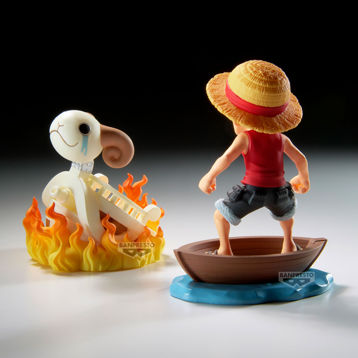 Statue di Luffy su una barca e una figura in fiamme. Luffy indossa un cappello di paglia. L'altra statua brucia.