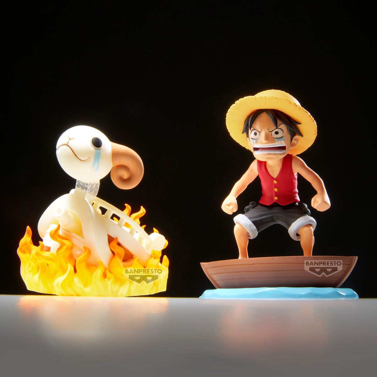 Statue: Luffy è in piedi su una barca, di fronte a una figura scheletrica in fiamme. Entrambi sono dell'anime One Piece. Sfondo nero.