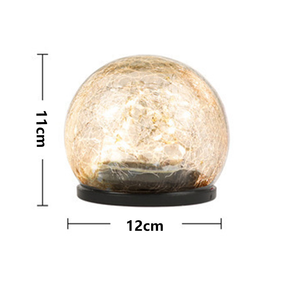 Eine kugelförmige dekorative Lampe mit Rissglas-Effekt. Sie ist 11 cm hoch und 12 cm breit. Sie steht auf einem schwarzen Sockel.