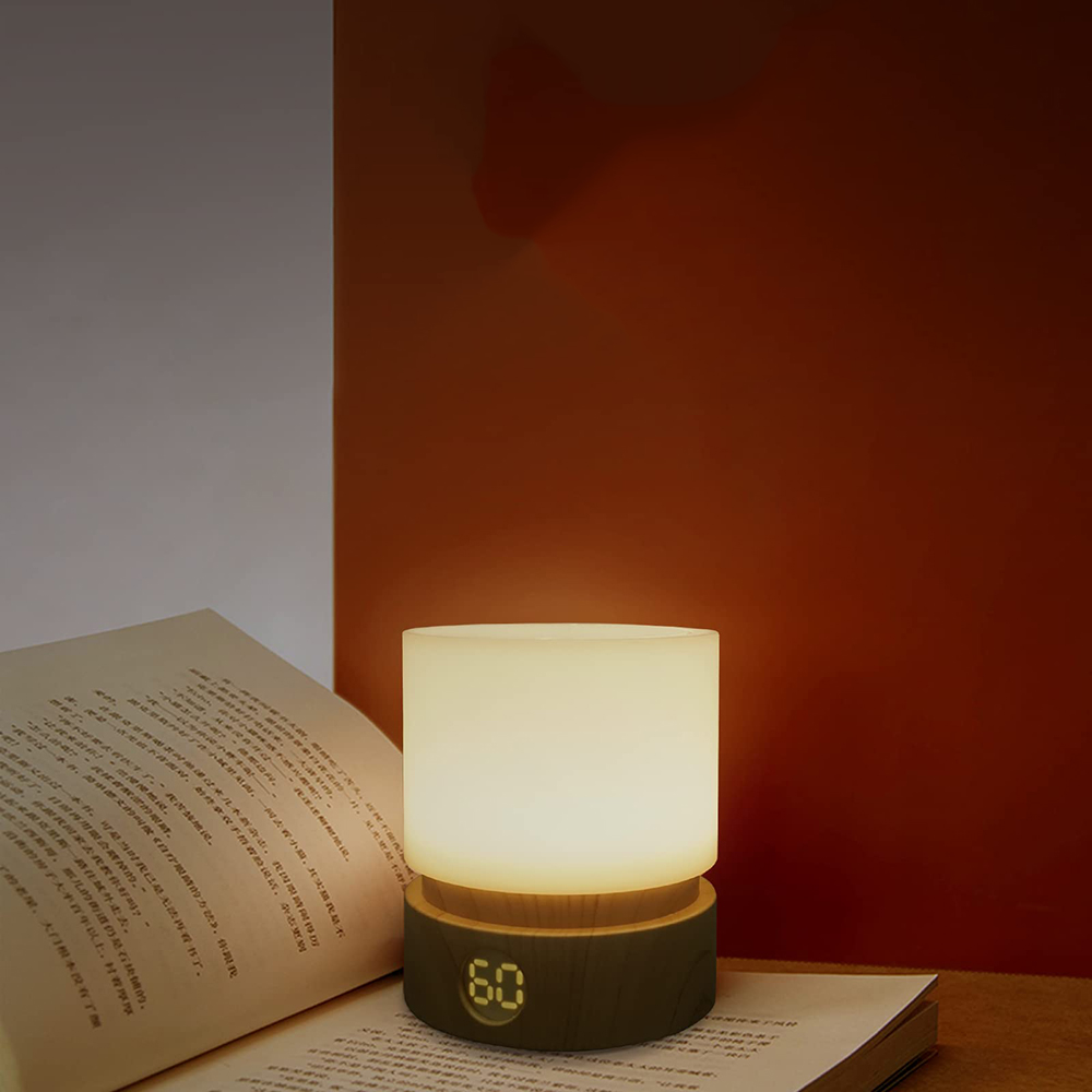 Eine beleuchtete Nachttischlampe mit digitaler Anzeige '60' steht auf einem Buch. Der Hintergrund ist eine Wand, teilweise im Schatten.