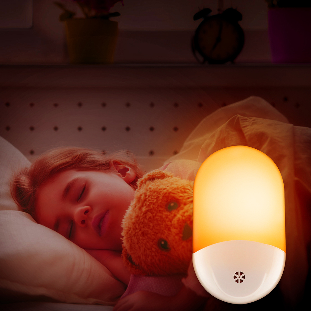 Ein schlafendes Kind mit einem Teddybären unter einer Decke, daneben ein leuchtendes Nachtlicht. Im Hintergrund ein Regal.