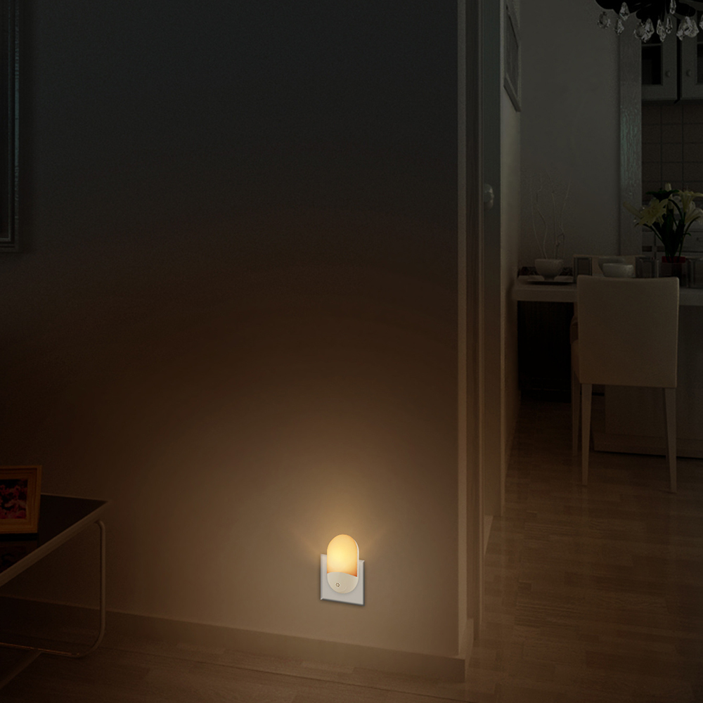 Ein Nachtlicht leuchtet sanft an einer Wand. Im Hintergrund sind ein Flur mit Tisch und ein Essbereich zu sehen.