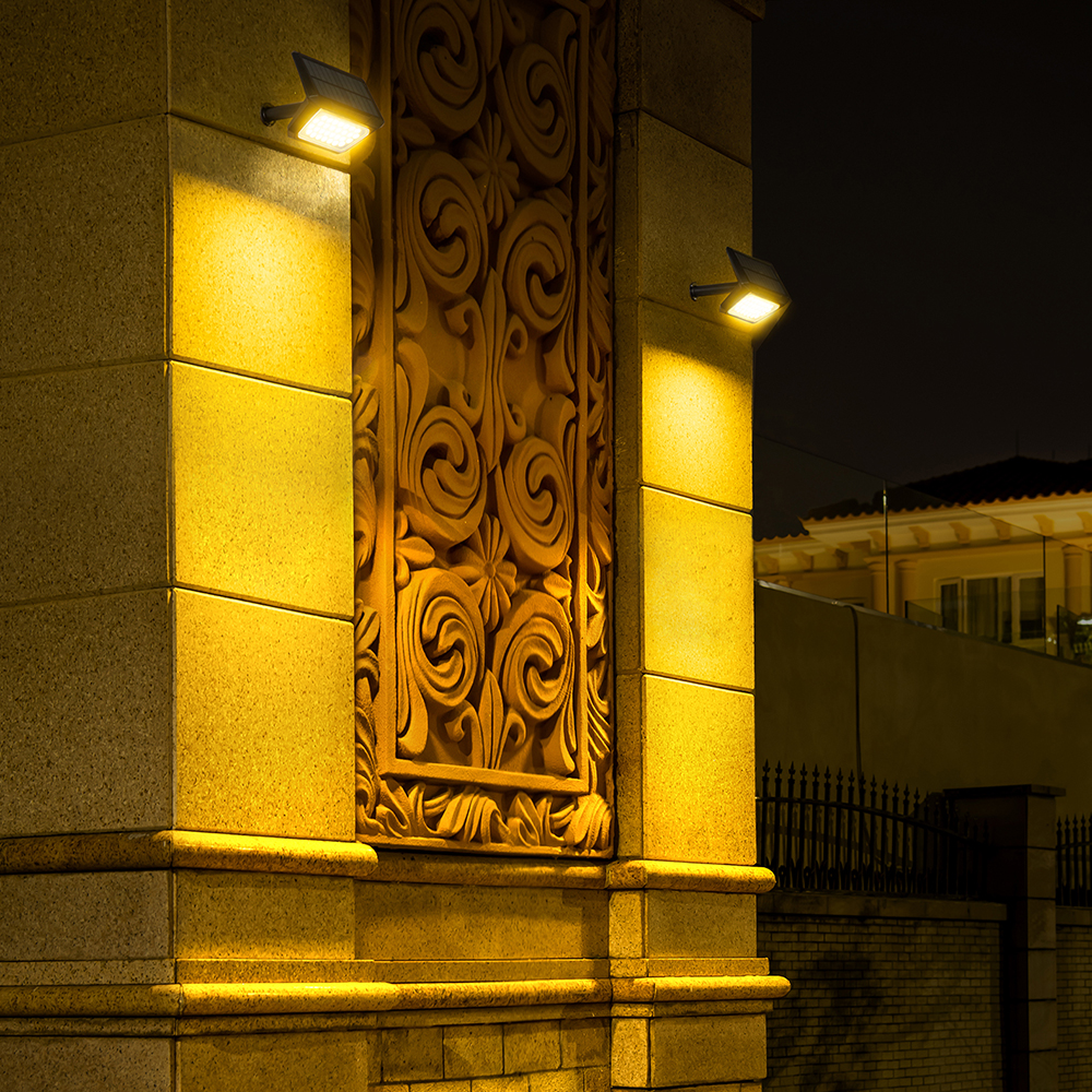 Verzierter Steinsäule mit Lichtern. Ein dekoratives Relief ist zentriert. Gebäude sind im Hintergrund, beleuchtet bei Nacht.