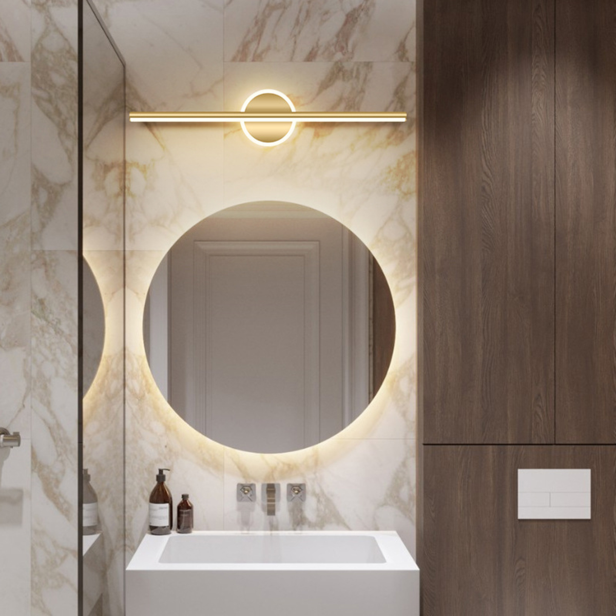 Badezimmer mit Marmorwänden, rundem Spiegel und Holzschrank. Ein Waschbecken mit Seifenflaschen und eine Leuchte über dem Spiegel.