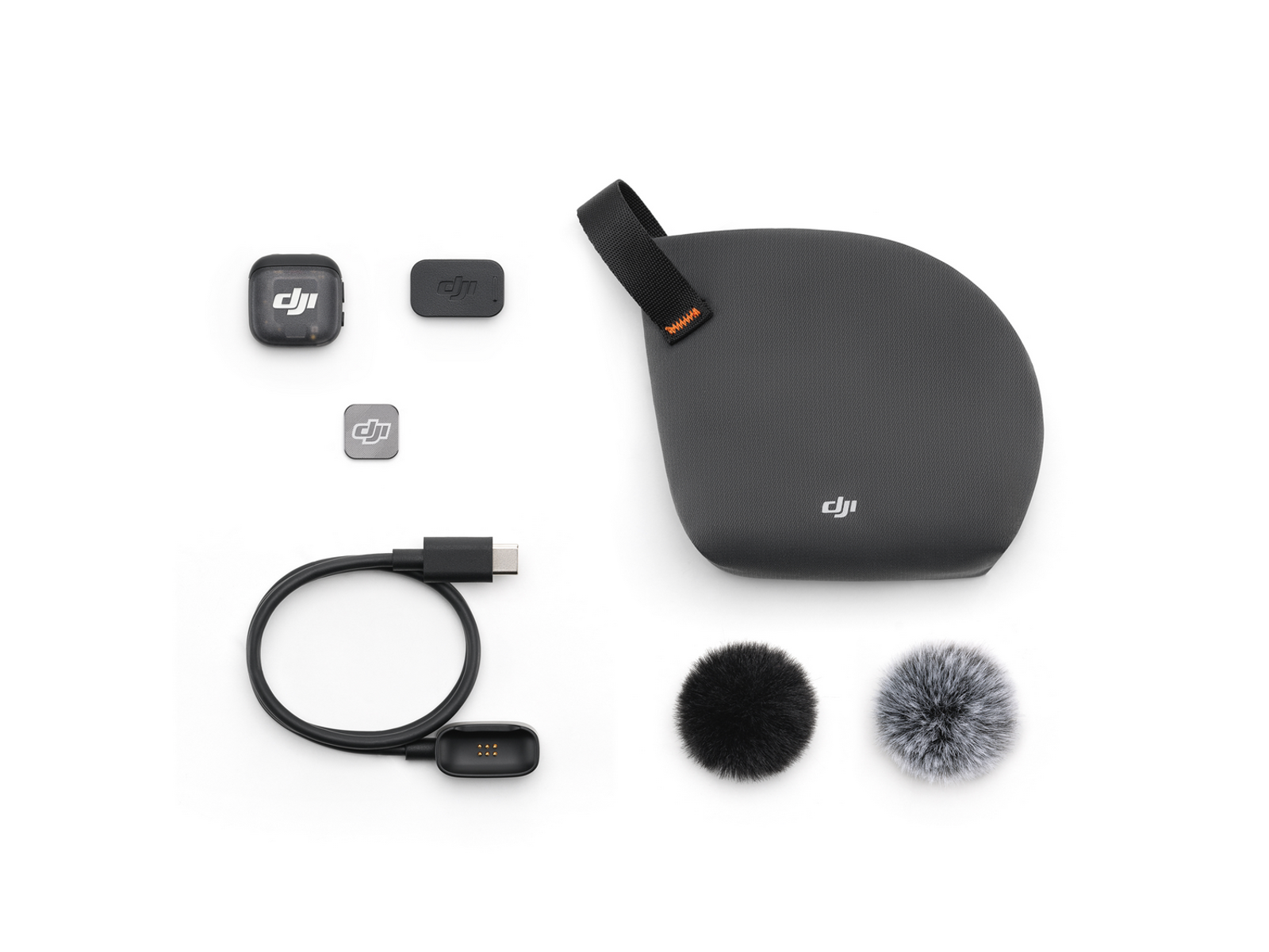 DJI audio-opnamekit op wit. Bevat microfoons, oplaadcase, kabel en windbeschermers. Zwarte en grijze componenten zijn zichtbaar.