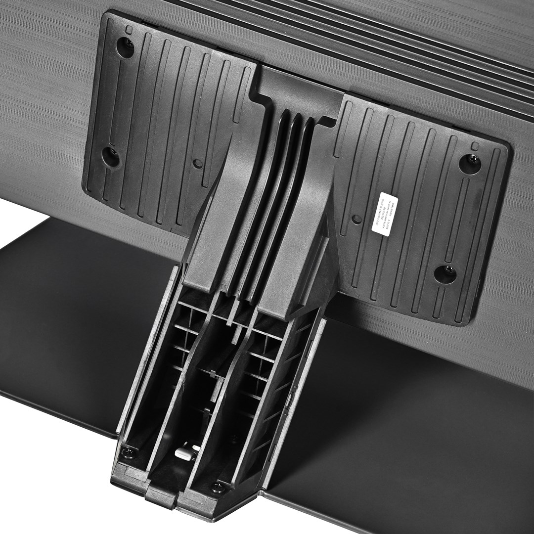 Zbliżenie czarnego stojaka pod telewizor. Stojak składa się z plastikowych części, z konstrukcją nośną i podstawą, zamontowaną na telewizorze.