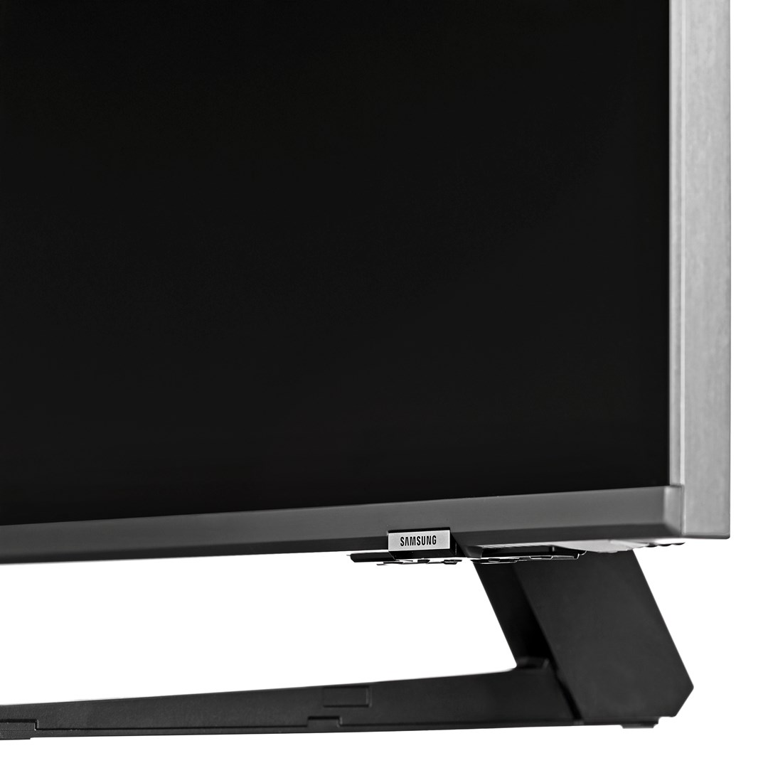 Close-up of a Samsung TV. The screen is black, with a silver frame and a black stand. The Samsung logo is visible.