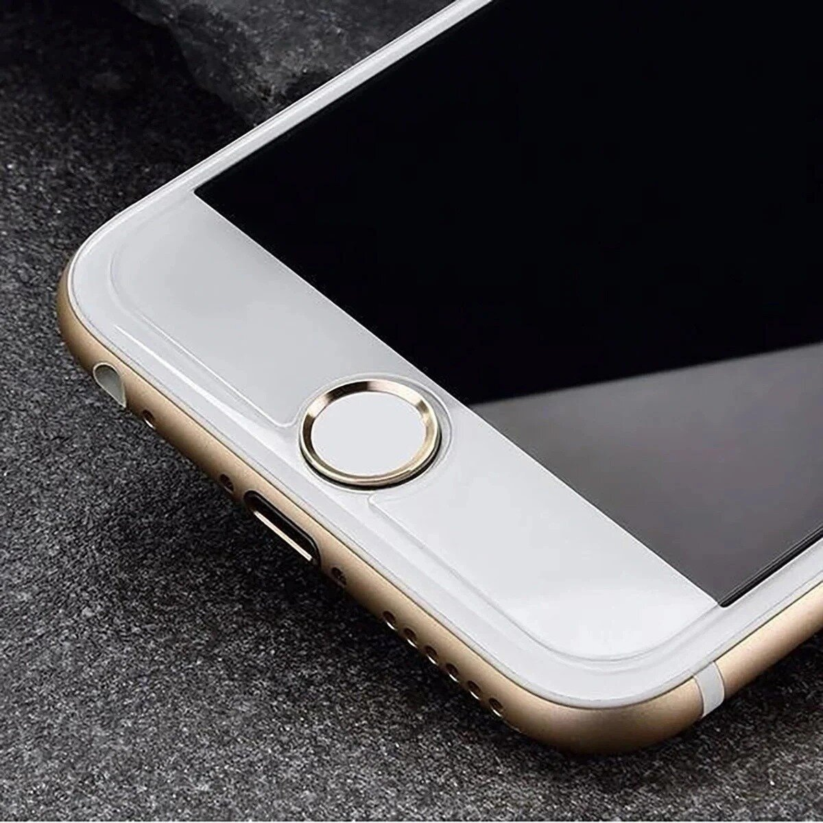 Close-up van een smartphone. Gouden frame met witte bovenkant en zwart scherm. Homeknop aanwezig. Op een grijs oppervlak.