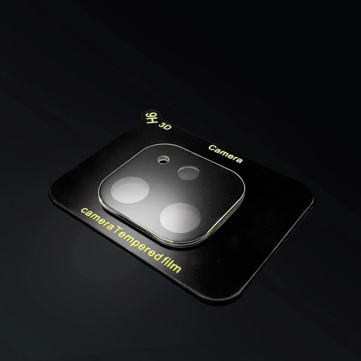A camera lens protector. It has a black base and a transparent lens cover with three circles and a small hole.