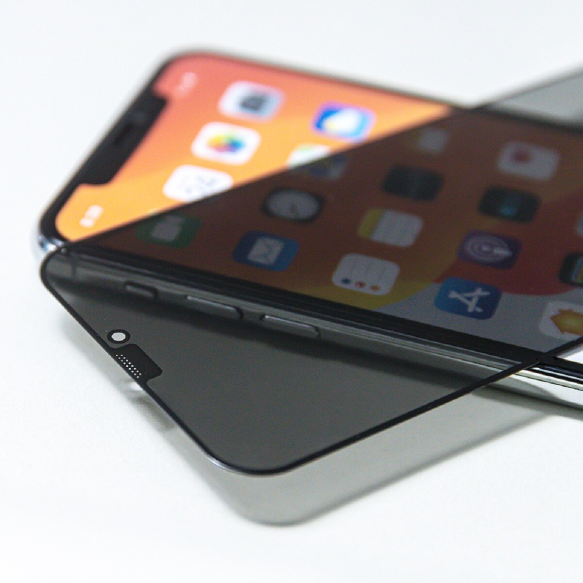 Un smartphone avec un protecteur d'écran appliqué. Le téléphone affiche des icônes d'applications. Le protecteur est sombre et recouvre partiellement l'écran.