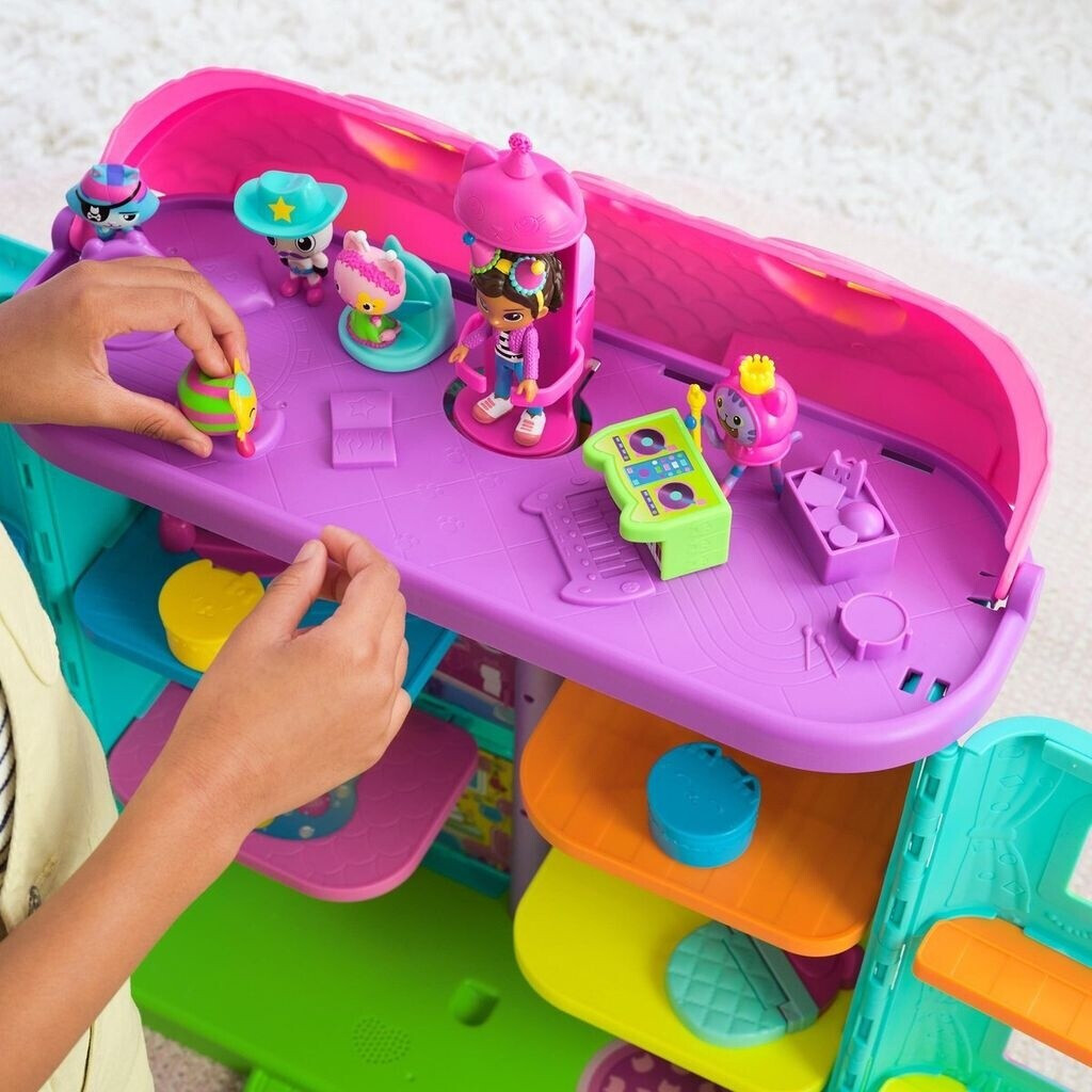 Ein Kind spielt mit einem bunten Spielzeug-Spielset mit Miniaturfiguren und Zubehör. Das Spielset hat mehrere Ebenen und ein rosa Dach.
