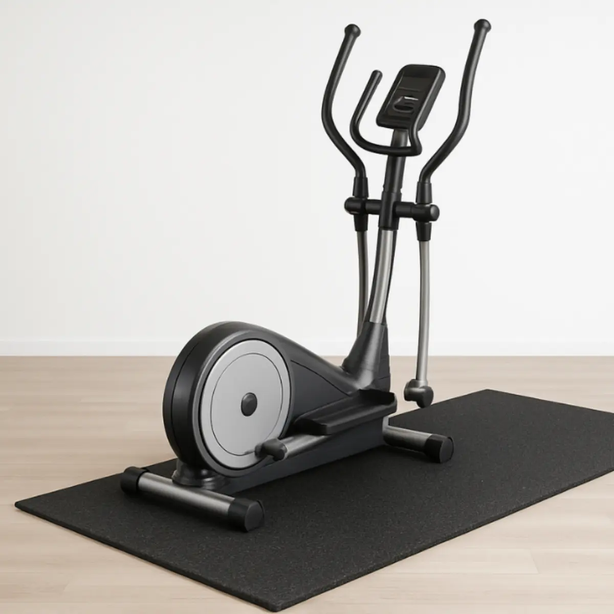 An elliptical machine on a black mat, set against a white wall and wood floor. The machine is black and silver.