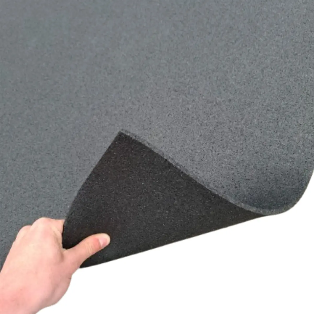 A hand lifts a corner of a dark gray, textured mat. The mat has a dark, rough underside. White background.