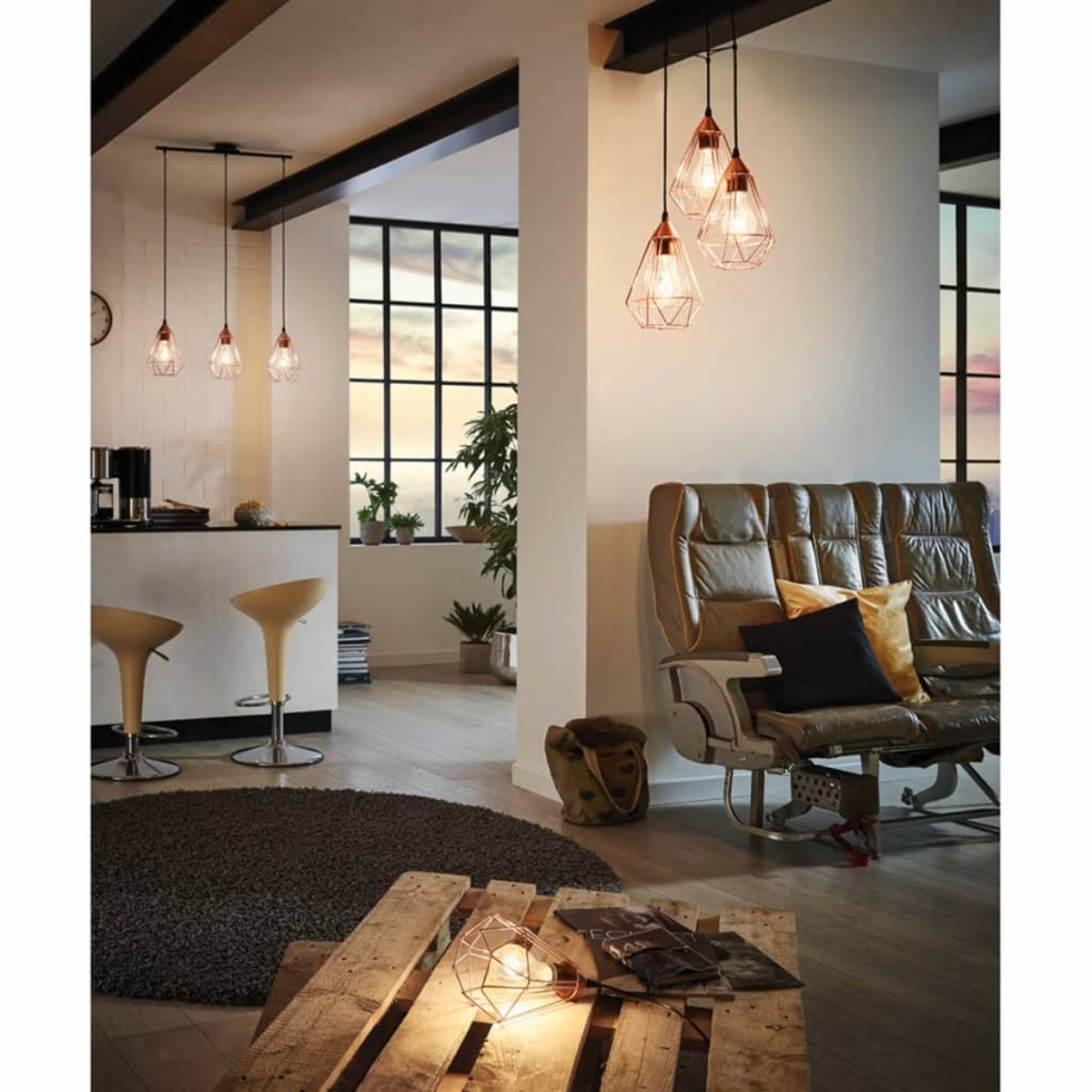 Modernes Wohnzimmer mit Pendelleuchten, Ledersofa, Couchtisch aus Holzpaletten und einem Barbereich. Natürliches Licht durch große Fenster.