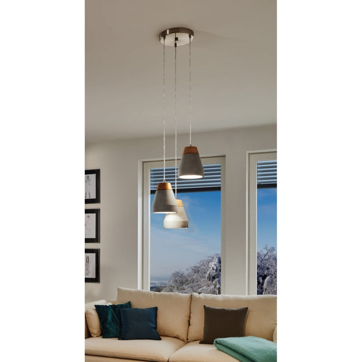 Drei Pendelleuchten hängen über einem beigen Sofa. Ein Fenster zeigt eine verschneite Landschaft. Kissen liegen auf dem Sofa.