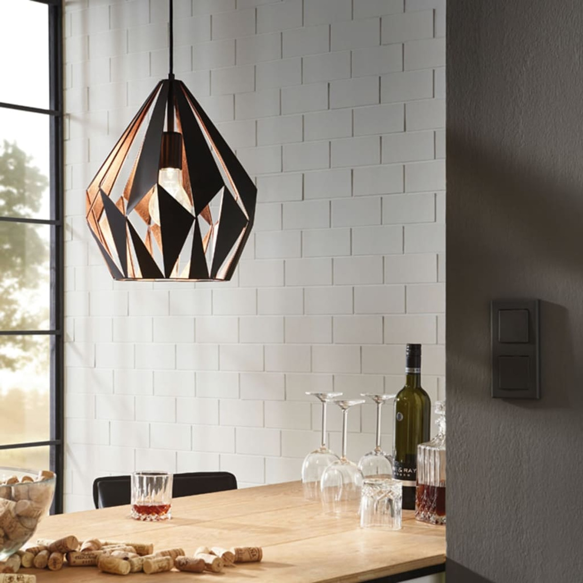 Eine Essszene mit einer modernen geometrischen Lampe, einem Tisch mit Weingläsern, einer Weinflasche und einem Glas roter Flüssigkeit.