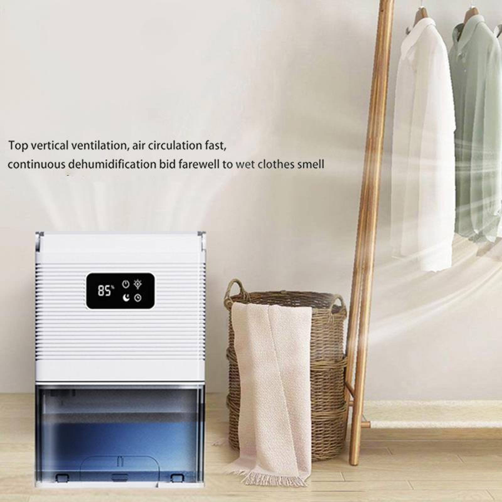 Ein weißer Luftentfeuchter mit digitaler Anzeige 85, eine Kleiderstange mit Hemden und ein Korb mit einem Handtuch.