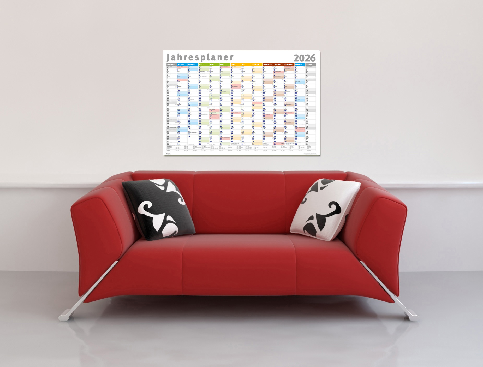 Ein rotes Sofa mit Kissen, ein Kalender 2026 an der Wand. Der Raum ist weiß und grau.