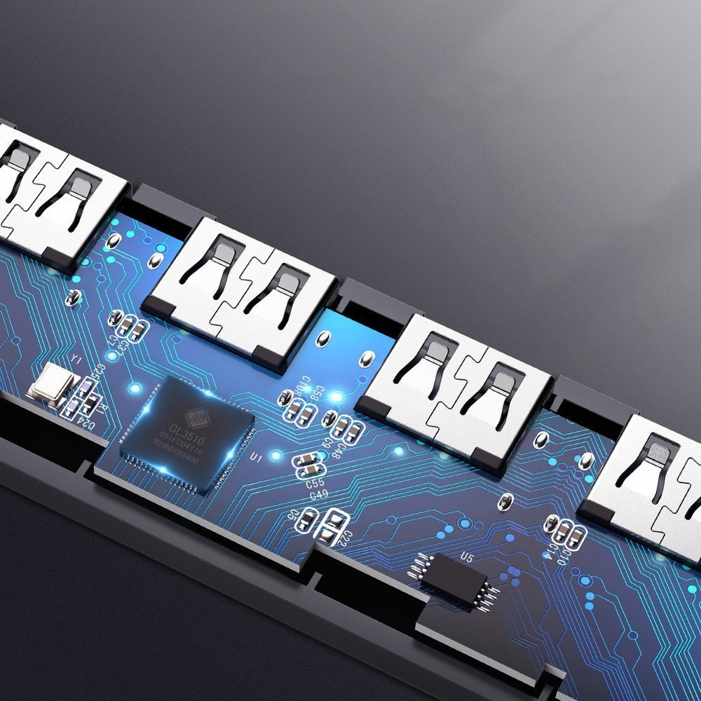 Zbliżenie na koncentrator USB z wieloma portami. Widoczna jest płytka drukowana z układami scalonymi i skomplikowanymi niebieskimi liniami. Porty są srebrne.