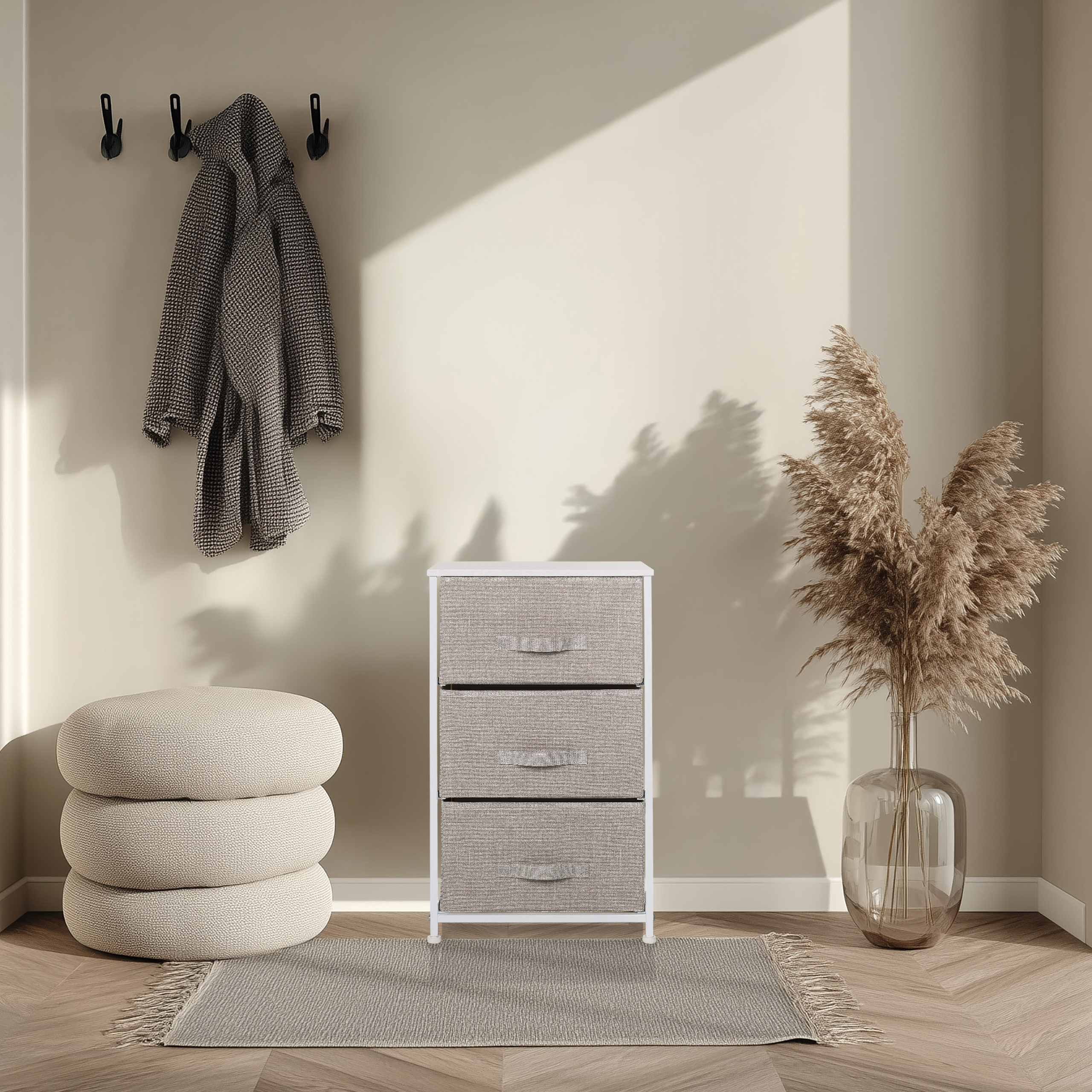 Ein Raum mit einer Kommode, einem Mantel, einem Teppich und einer Vase mit getrockneten Blumen. Die Wand ist beige und der Boden ist aus Holz.