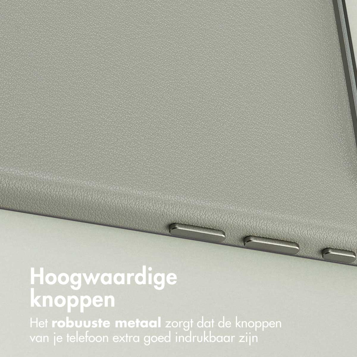 Close-up van een grijze telefoonhoes met drie metalen knoppen. De hoes heeft een textuur. Deels Nederlandse tekst zichtbaar.