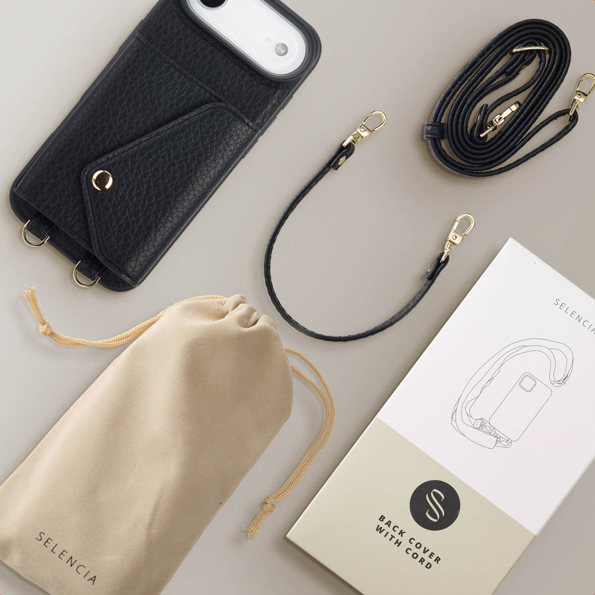 Coque de téléphone noire avec lanière, un petit sac et une brochure sur une surface gris clair. L'étui a une fente pour carte.