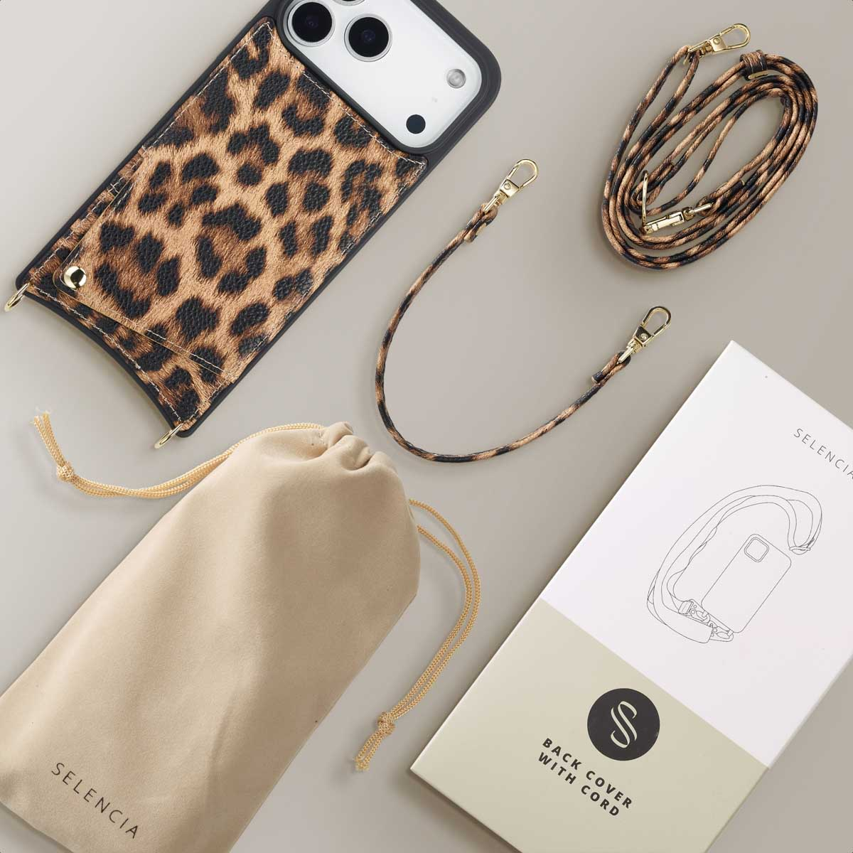 Telefoonhoesje met luipaardprint en koord, beige zakje en doos met diagram, alles op een lichtgrijze ondergrond.