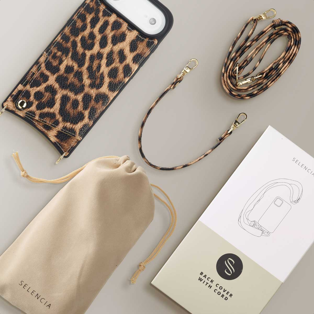 Coque de téléphone à imprimé léopard, sangle et sac à cordon sur une surface grise. Une boîte avec un schéma de coque de téléphone est également présente.