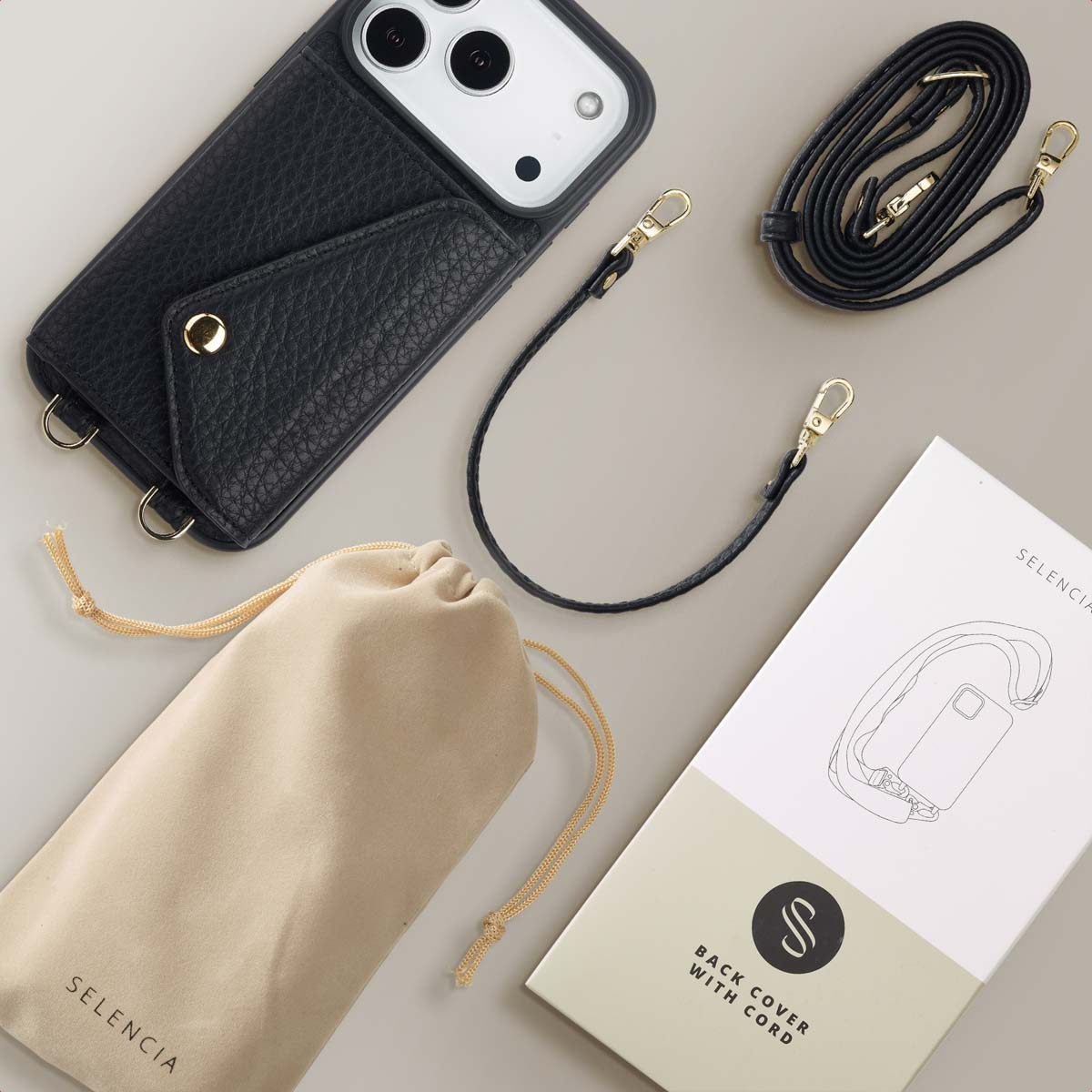 Zwarte telefoonhoes met riem, etui en doos. De hoes heeft een zak. De riem en hoes hebben gouden accenten. Beige etui met Selencia.