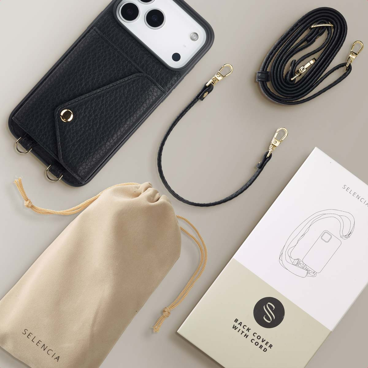 Coque de téléphone en cuir noir avec une sangle et une pochette, plus une boîte avec une illustration de coque de téléphone. Surface beige.
