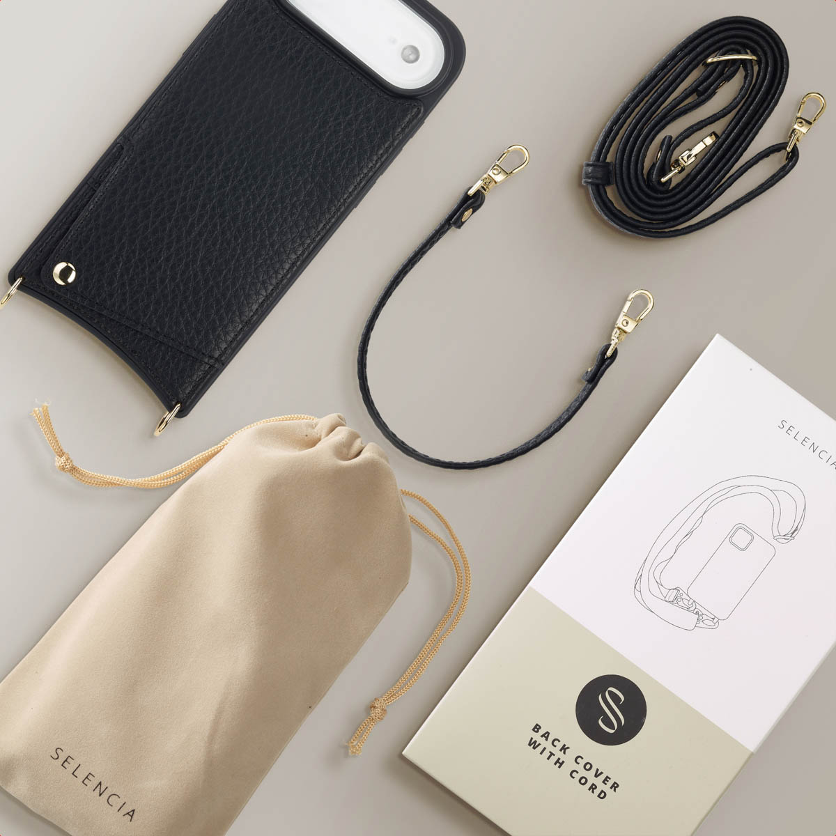 Coque de téléphone noire avec cordon, sangle, pochette beige et boîte produit disposés sur une surface grise.