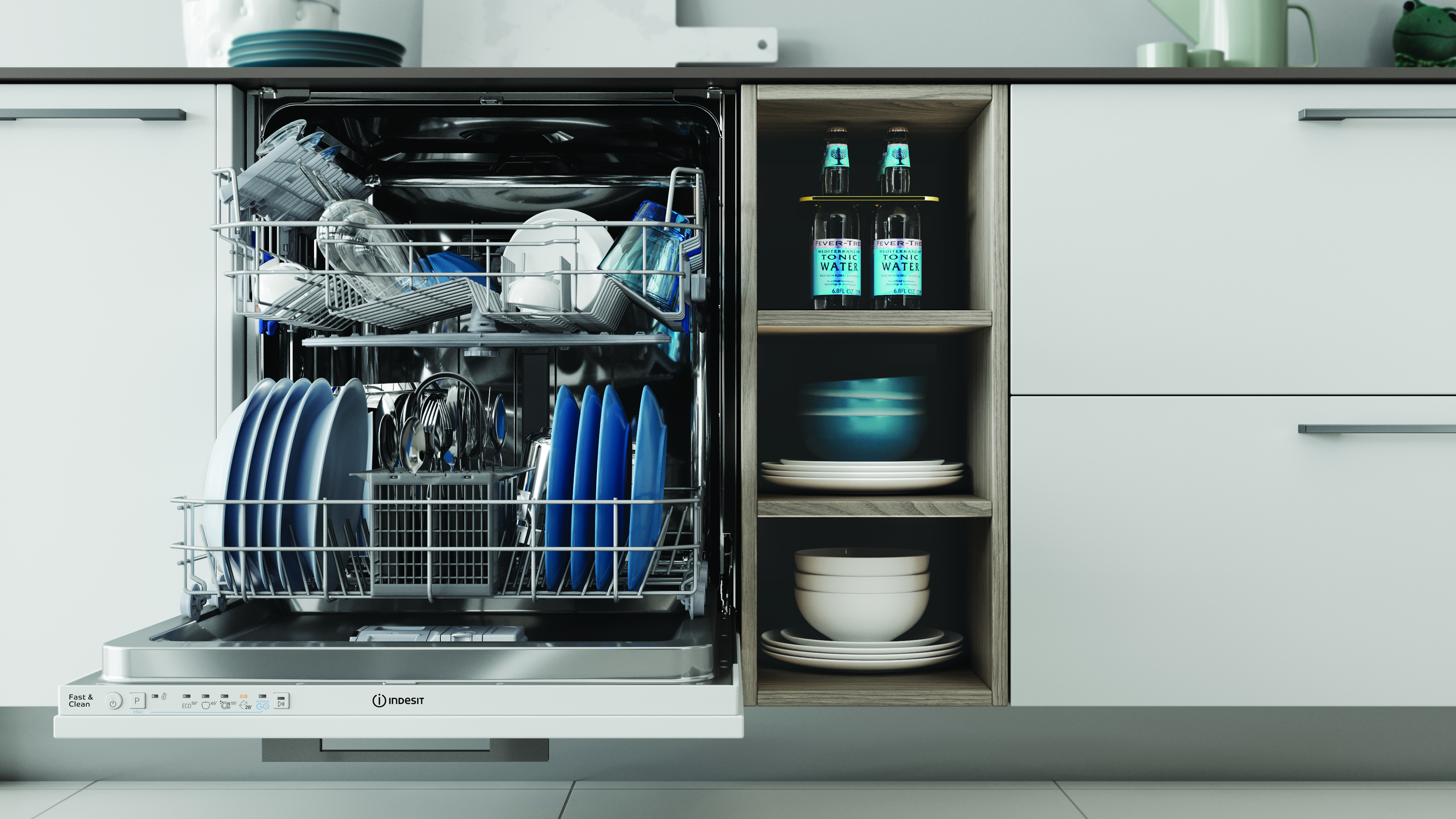 Otwarta zmywarka, wypełniona naczyniami. Obok półki z miskami i wodą tonizującą. Białe szafki otaczają scenę.