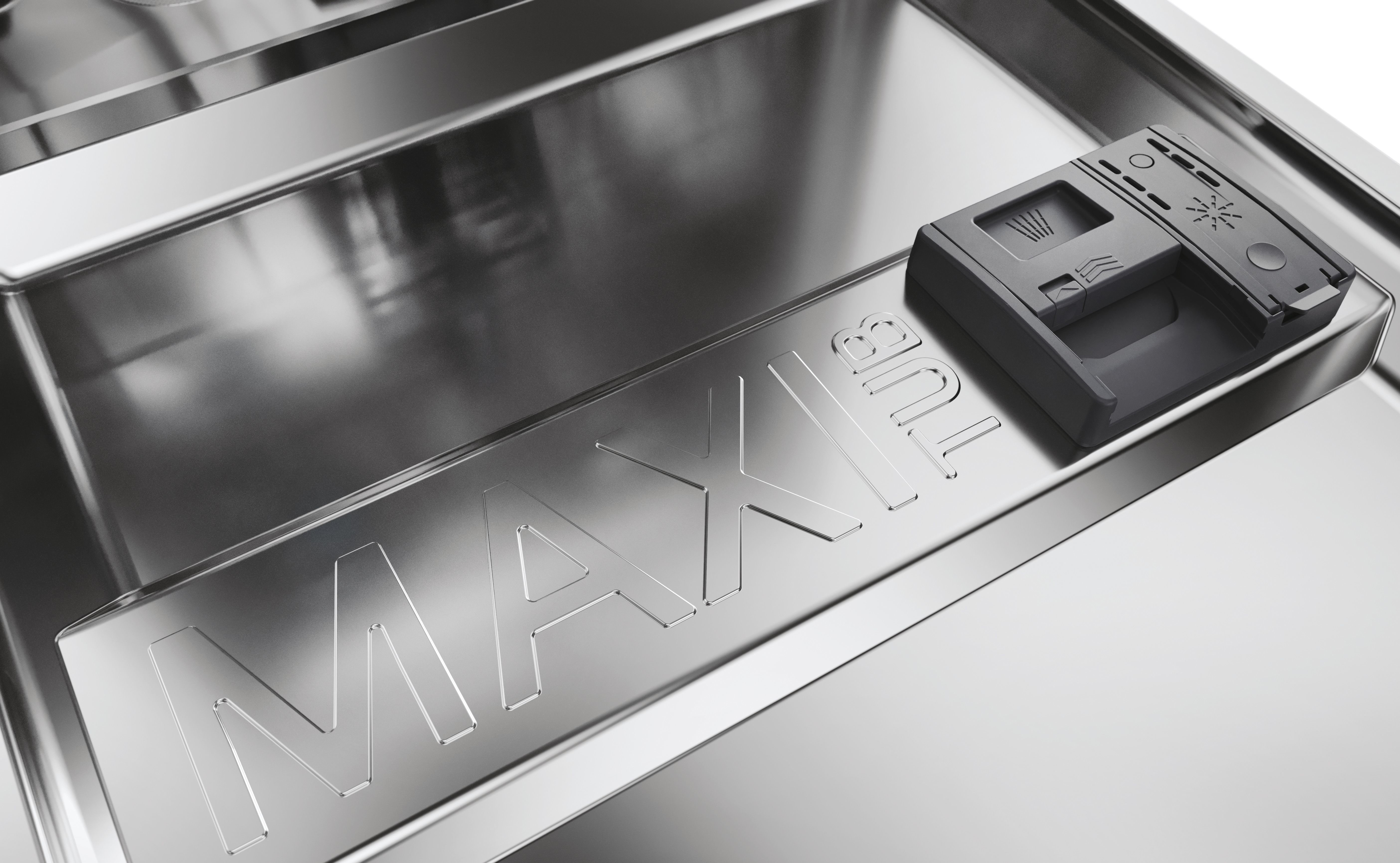 Primo piano dell'interno di una lavastoviglie. Il marchio MAX è visibile e presente un dosatore di detersivo.
