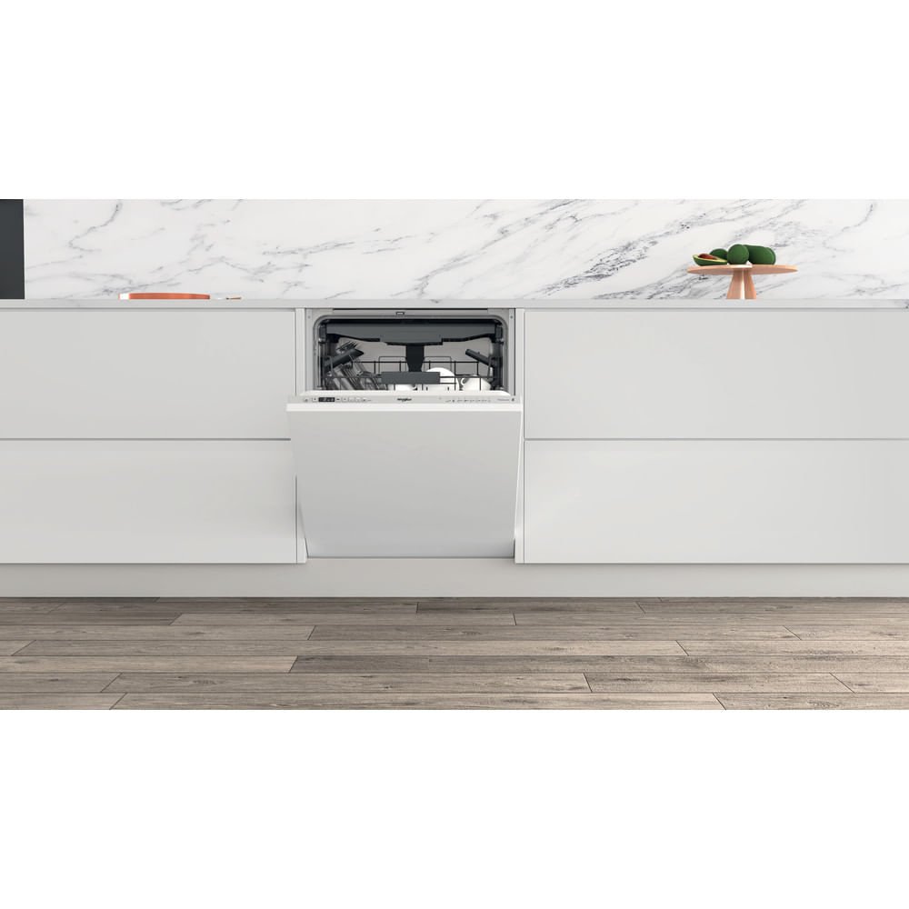 Un lavavajillas blanco, con la puerta abierta, está integrado en un mueble de cocina blanco. Suelo de madera y encimera de mármol.