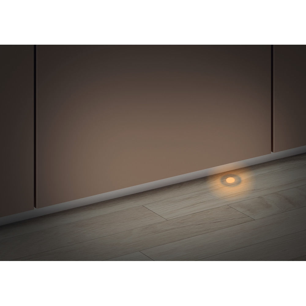 Una luz cálida brilla sobre un piso de madera. Un armario está arriba con una línea blanca que lo separa. La luz proviene de un pequeño círculo.