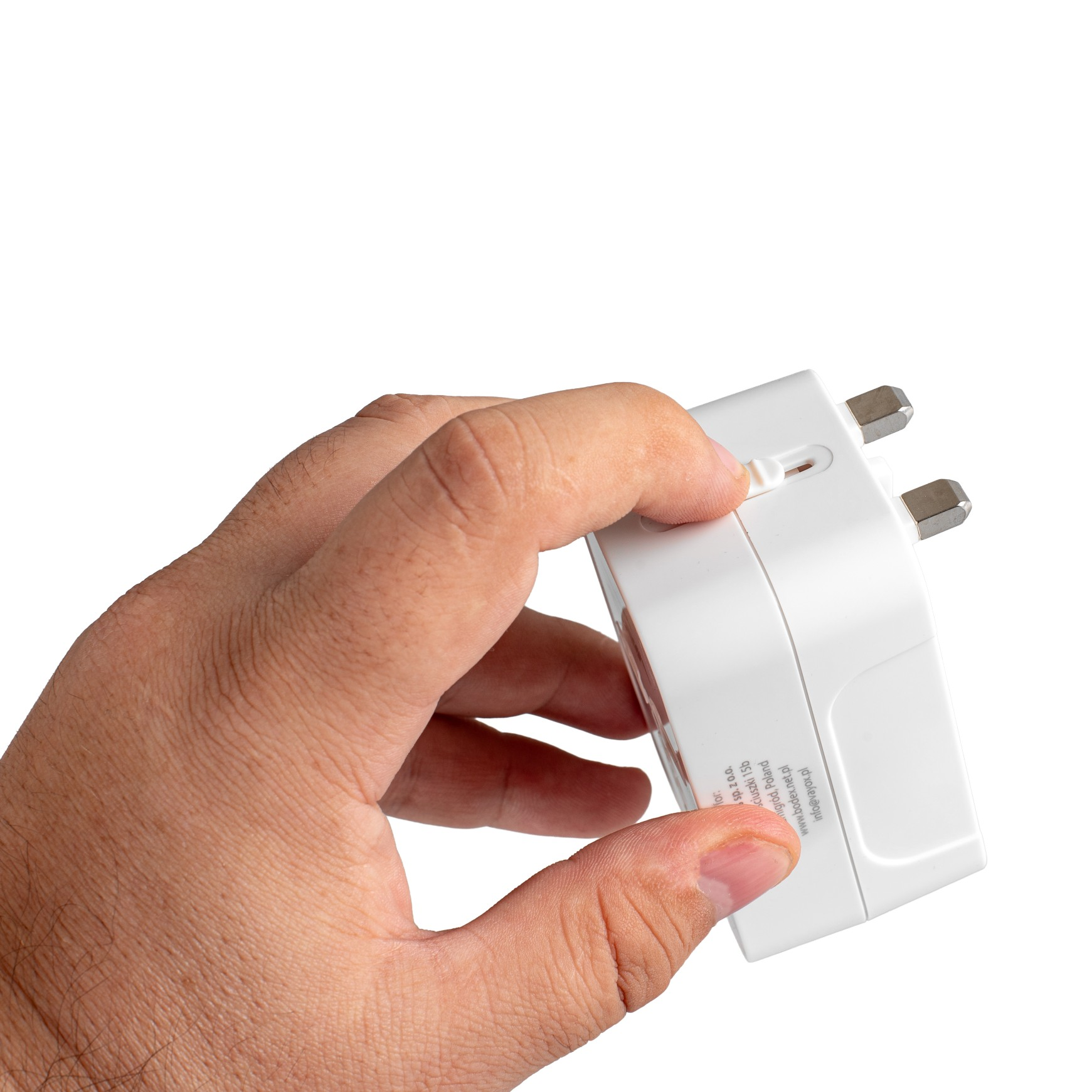 Ręka trzyma białą przejściówkę podróżną. Adapter ma srebrne bolce i przełącznik.