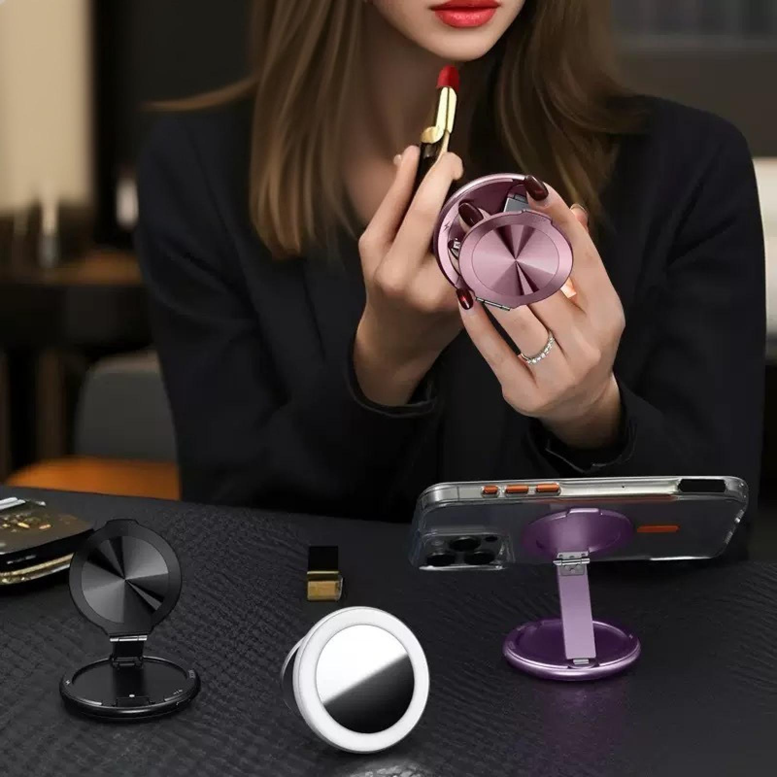 Eine Frau trägt Lippenstift auf, während sie ein Ringlicht und einen Telefonständer benutzt. Mehrere andere Ständer stehen auf dem Tisch.