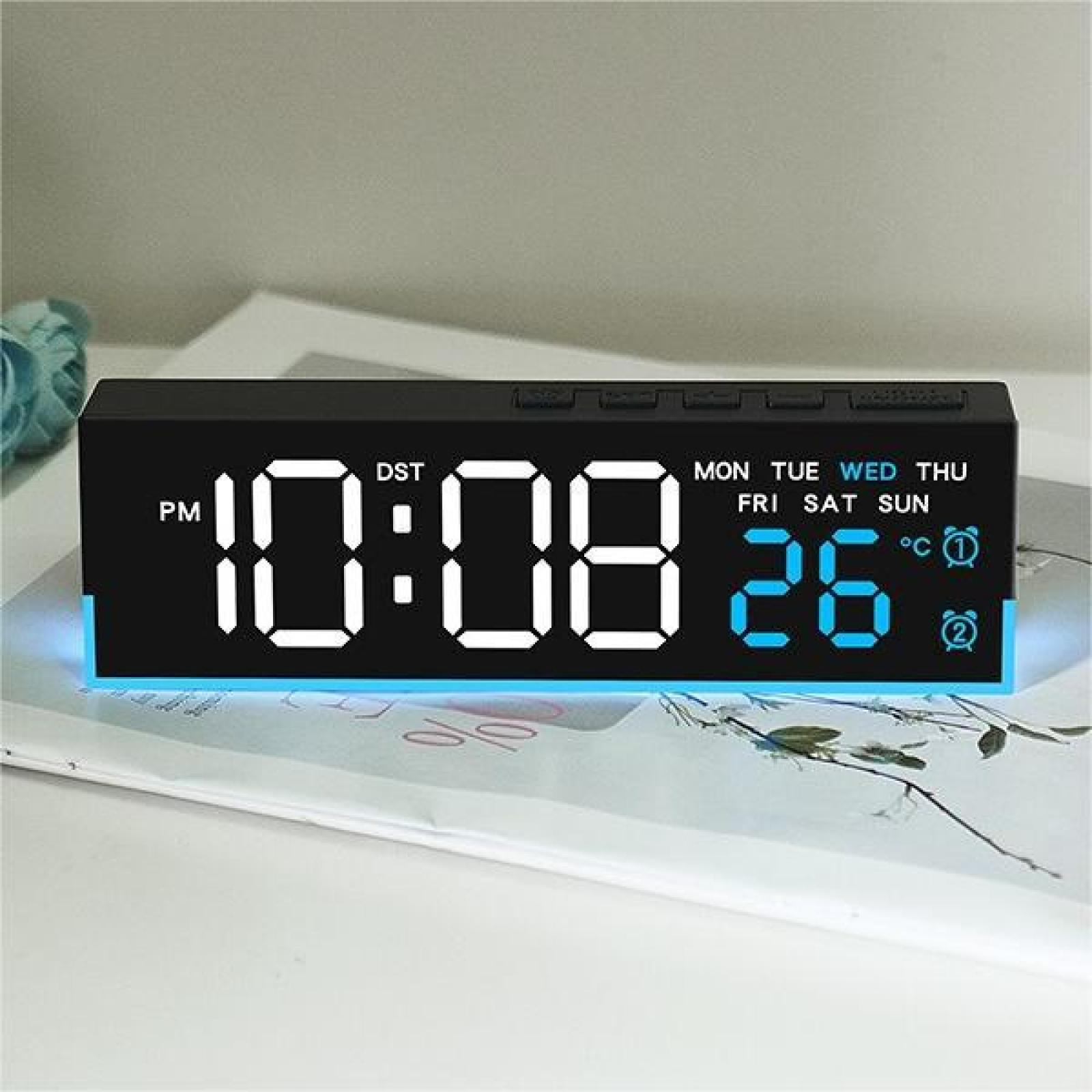 Eine schwarze Digitaluhr zeigt 22:08 Uhr und das Datum 26 an. Die Uhr steht auf einer weißen Oberfläche mit ein paar Blättern.